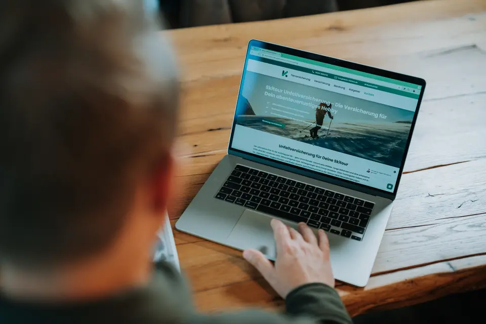 Denis Klefenz tippt von hinten auf einem Laptop und ruft die Website von Denis Klefenz auf